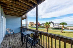 A wooden deck with a table and chairs, overlooking a body of water and houses. - Spacious studio condo with the best amenities in Port Aransas! (Port Aransas)