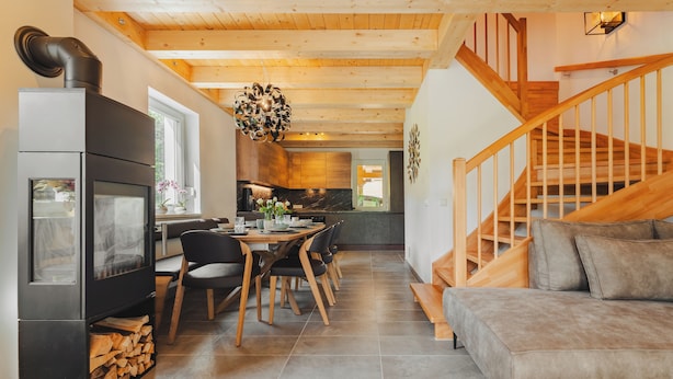 Eine moderne Küche mit Essbereich, einer Holztreppe und einem Kamin.