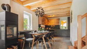 Eine moderne Küche mit einer zentralen Kochinsel, Holzbalkendecke und einem Essbereich mit Tisch und Stühlen.