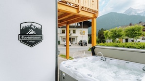Ein Holzbalkon mit Whirlpool, einem Schild für das Noordermoorer Cottage und einer Bergsicht im Hintergrund.