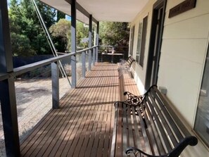 A wooden deck with benches, a table, and a covered area with a view of trees. - Carnegie House 3 Carnegie St Fully Fenced (Port Elliot)