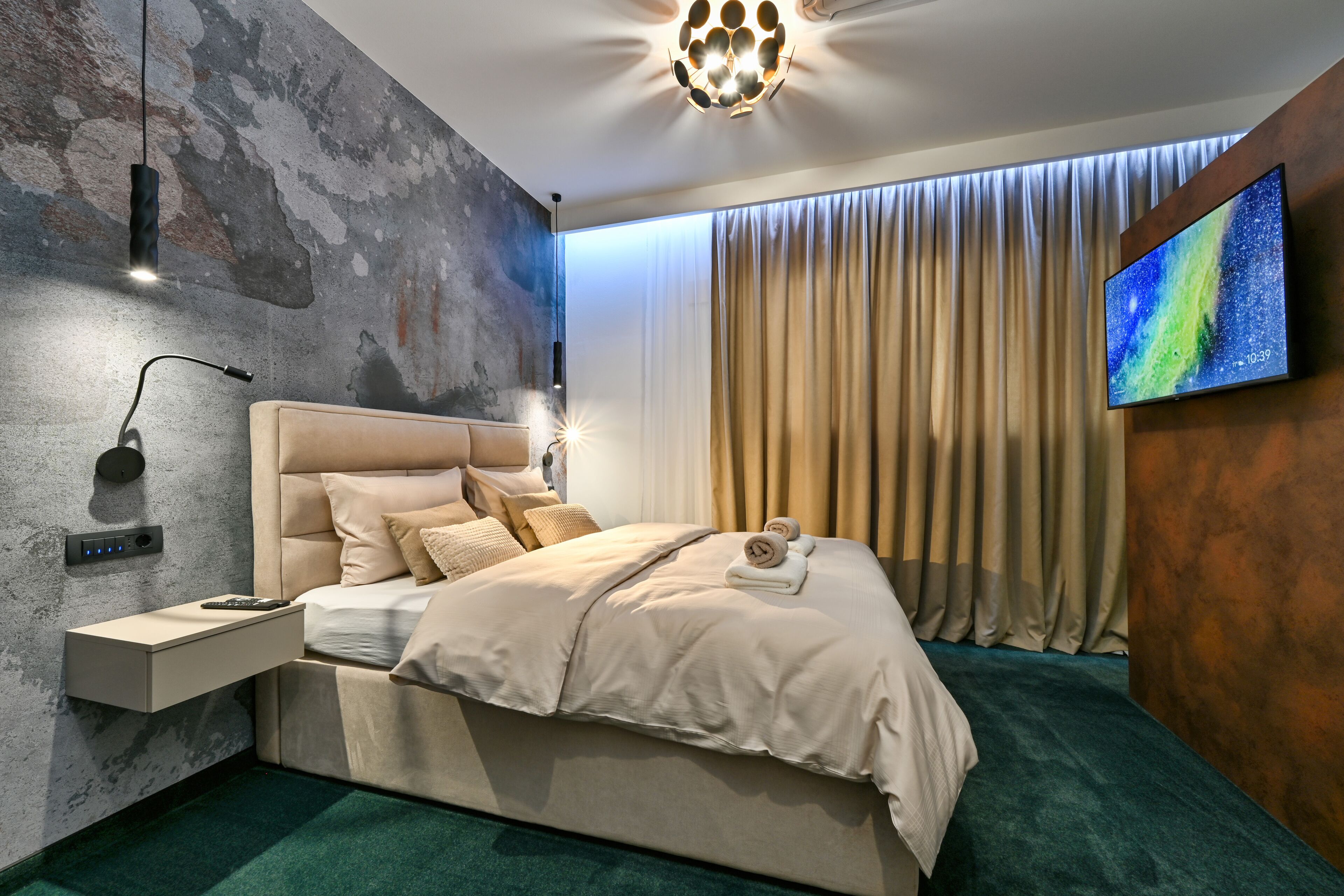 Ein modernes Schlafzimmer mit Bett, Nachttisch und einem an der Wand befestigten Fernseher.
