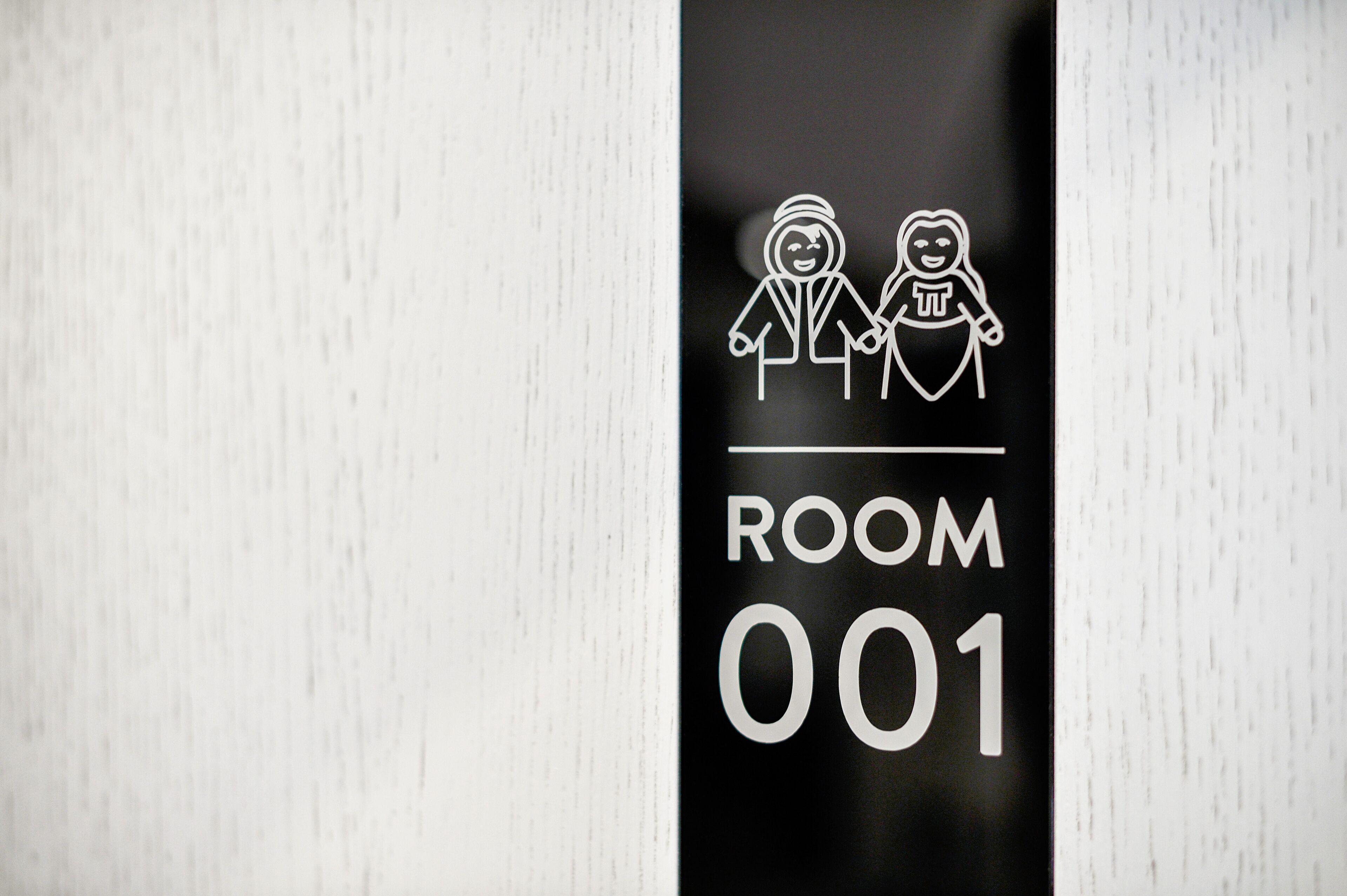 Un letrero con dos figuras estilizadas, una en silla de ruedas, y el texto 'ROOM 001'.