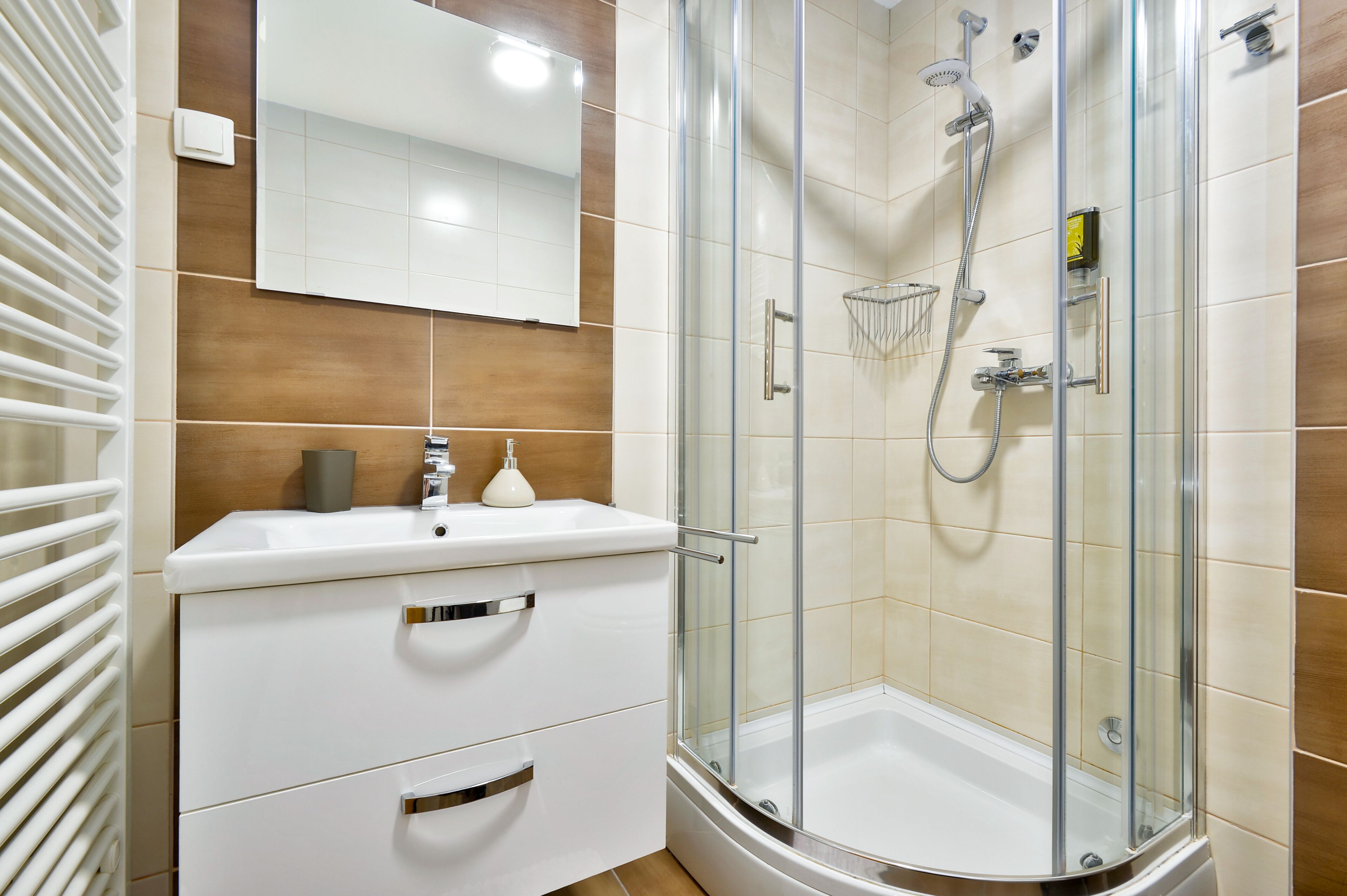 A bathroom with a glass-enclosed shower, a white sink, and a mirror above the sink.