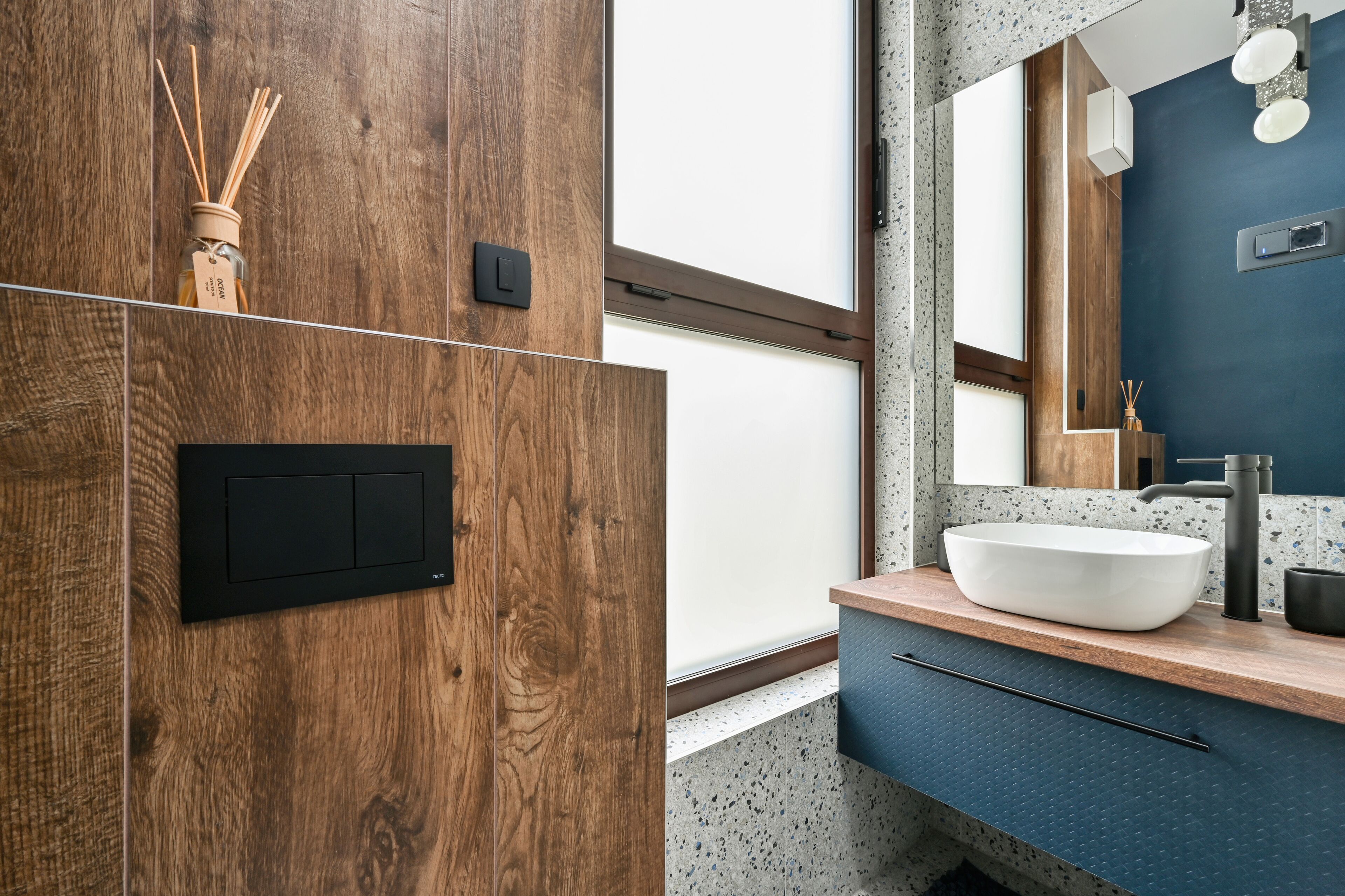 Un baño moderno con tocador de madera, un lavabo blanco tipo cuenco y un espejo grande.
