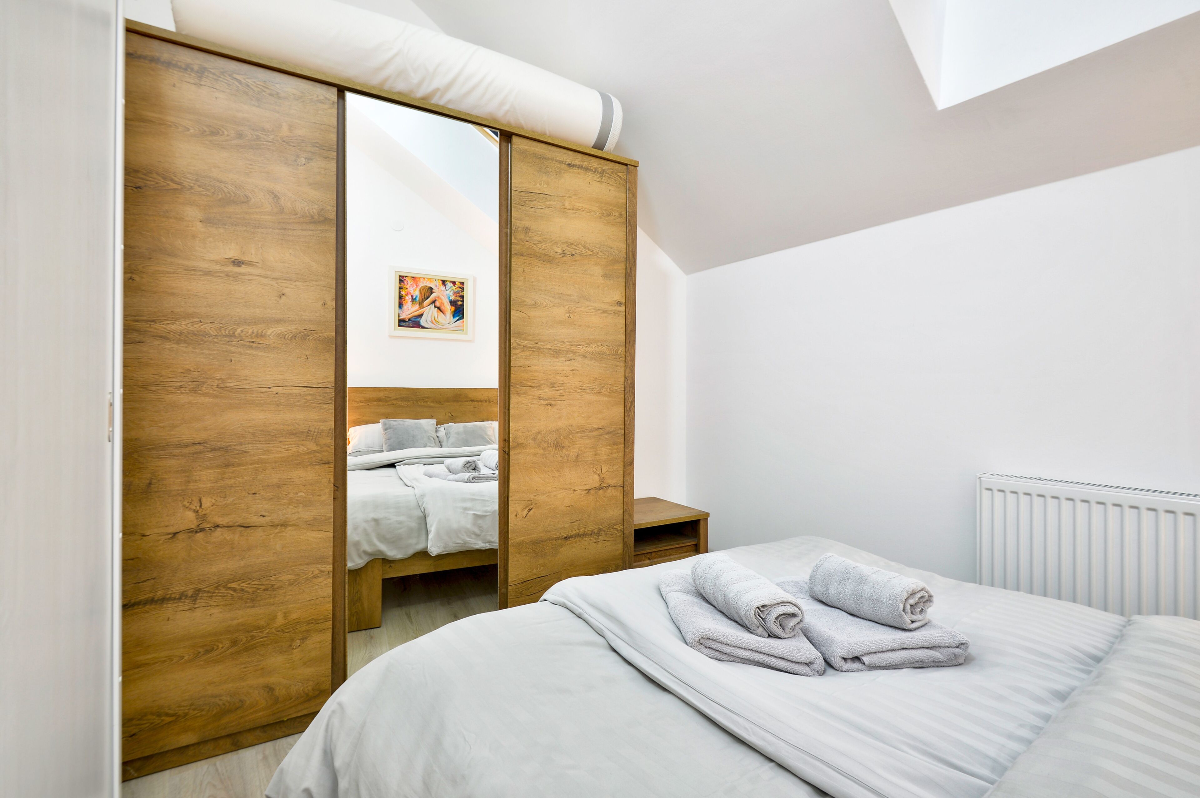 Ein Schlafzimmer mit Holzschrank, einem Bett mit weißen Bettwäsche und einer Heizung.