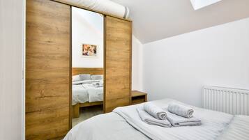 Ein Schlafzimmer mit Holzschrank, einem Bett mit weißen Bettwäsche und einer Heizung.