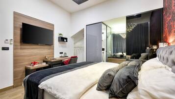 Quarto de hotel moderno com uma cama grande, televisão de tela plana na parede, escrivaninha com cadeira e closet espaçoso.