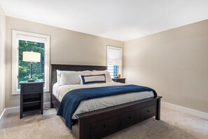 A bedroom with a bed, nightstands, and a window with a view of trees.