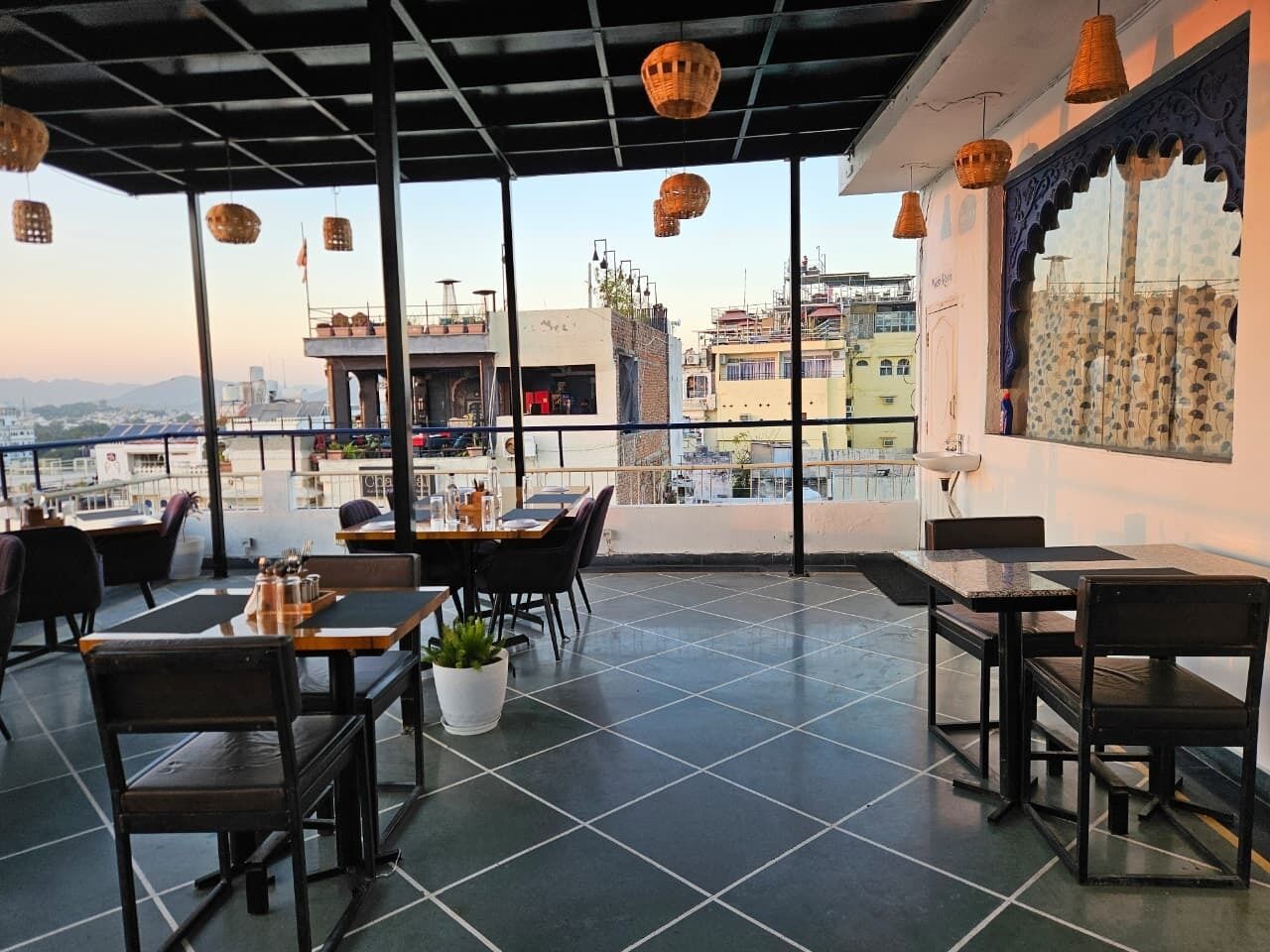 Un espace de restauration en plein air avec des tables et des chaises, un pot de fleurs et une vue sur le paysage urbain.