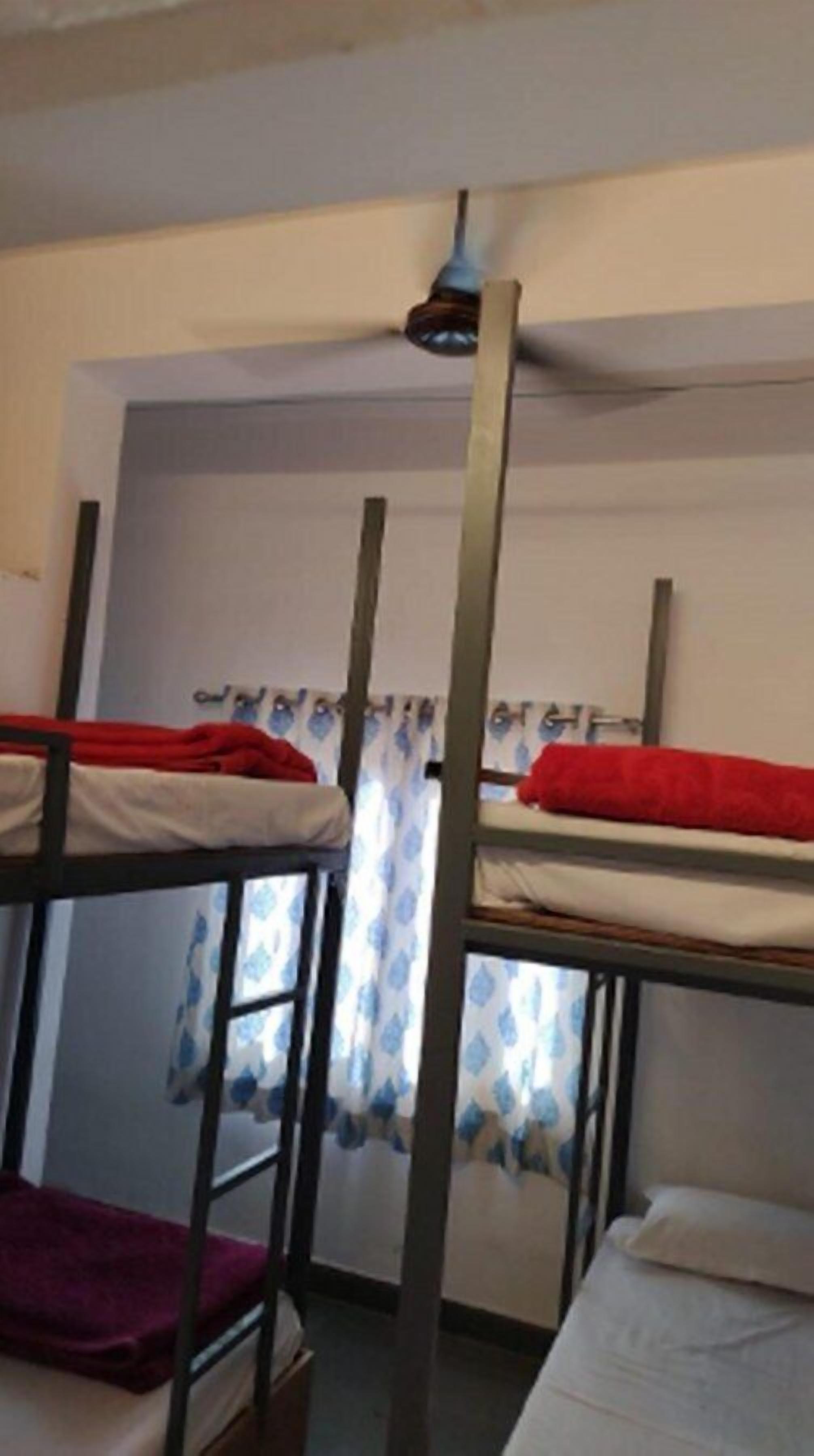 Dormitorio con literas, una ventana con cortinas y una lámpara en el techo.