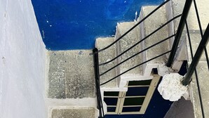 Una escalera con techo azul y paredes blancas que conduce a un interior oscuro.