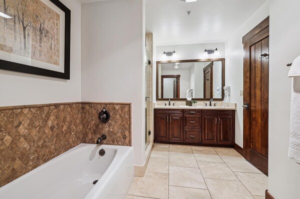 A modern bathroom with a freestanding bathtub, a large mirror, and wooden cabinetry.