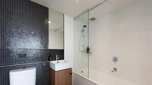 A modern bathroom with a glass-enclosed shower, white sink, and a wooden cabinet. - Stylish 2-bed Apt in Southbank With Parking (Southbank)