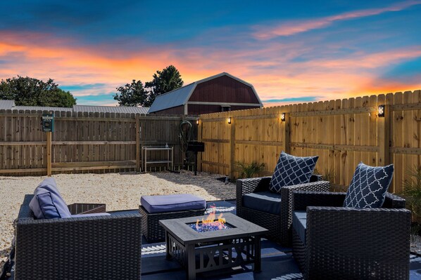 An outdoor patio with wicker furniture, a fire pit, and a wooden fence. - 🧜🏼♀️Mermaid Kisses-St Andrews Charmer!! Sleeps 8 and 10 minutes to the 🏝️ (Panama City)