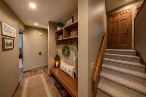 A hallway with a bench, a door, and a staircase.