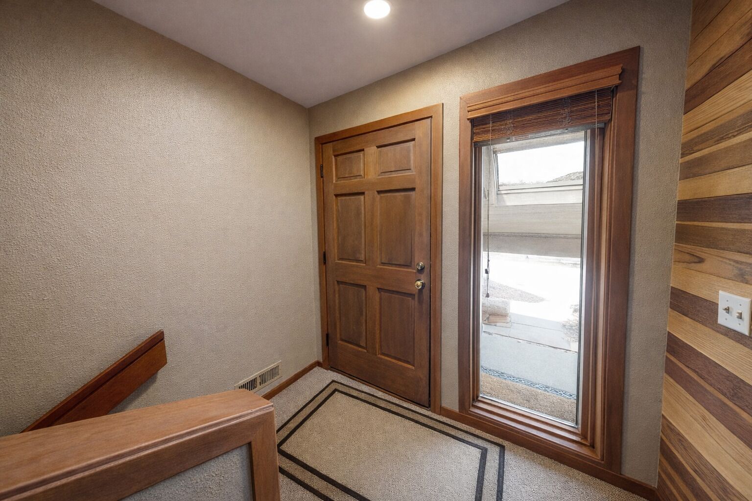 A hallway with a wooden door, a glass door, and a wooden bench.