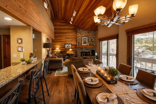 A dining area with a long table set for six, a fireplace, and a stone wall.