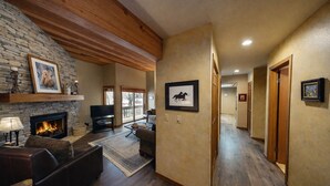 A spacious living room with a stone fireplace, a television, and a fireplace mantel. - 1791 Lakeside Getaway At Deer Valley! Outdoor Heated Pool & Hot Tubs! 2 Bedroom Condo by RedAwning (Park City)