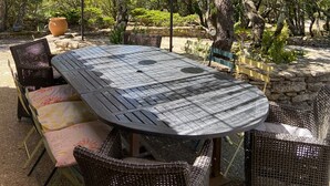 Eine Terrassengaststätte mit Tisch und Stühlen, umgeben von Bäumen und einem Reetdach.