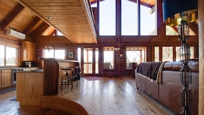 A spacious log cabin interior with a kitchen, dining area, and a large windowed living room. - Private 40-Acre Ranch + Pool, Sauna w/ Yurt (Sisters)