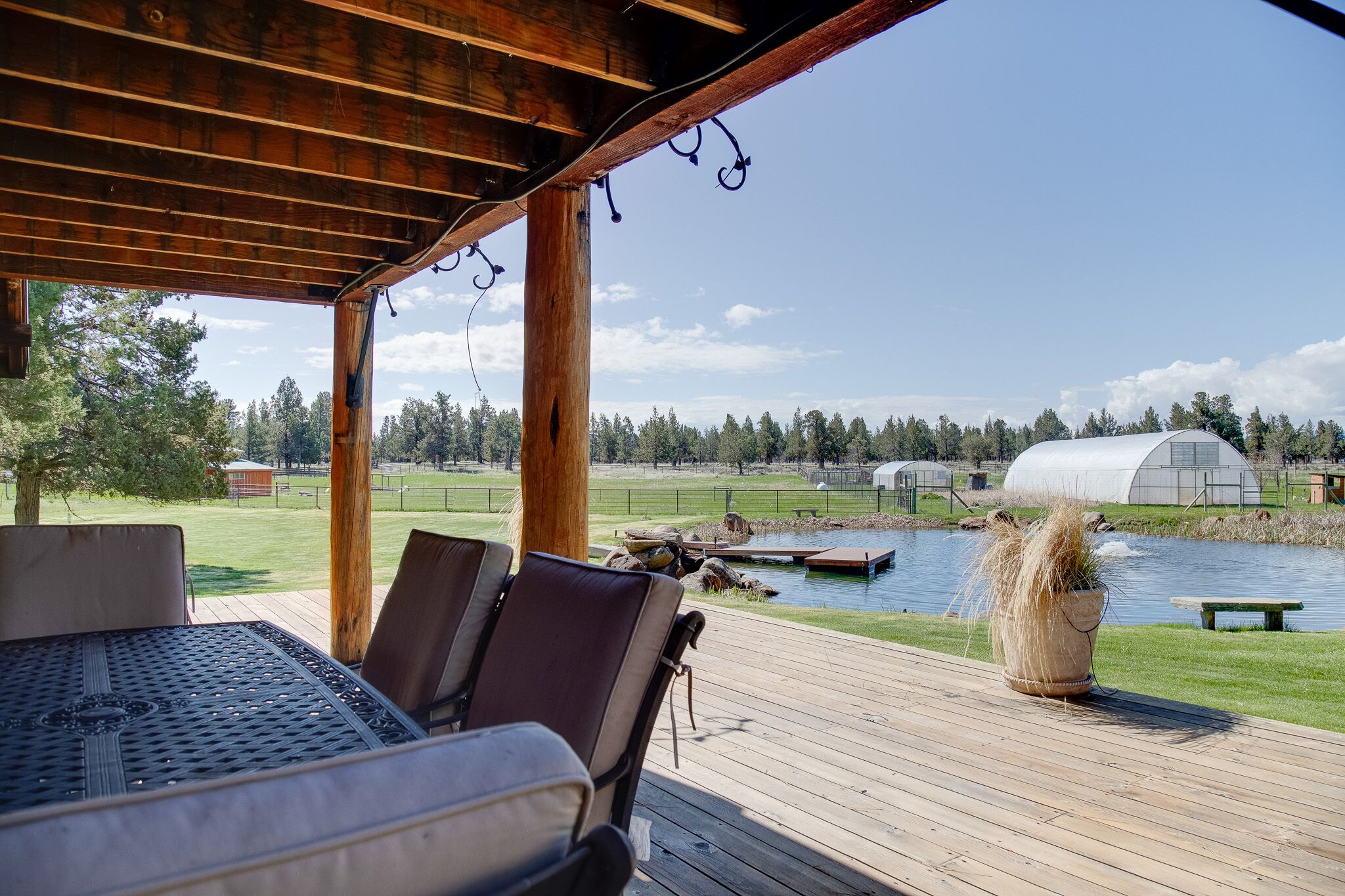 Un espace extérieur abrité, aménagé pour s’asseoir, avec vue sur un lac et une serre.