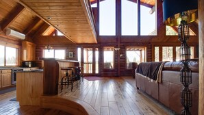 A spacious log cabin interior with a kitchen, dining area, and a large windowed living room. - JJ Ranch 40 acres 5 bdrm 3 bath private pool, sauna, soaking tub Mountain Views (Sisters)