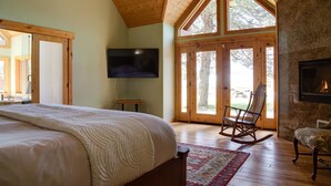 A bedroom with a large bed, a television, a rocking chair, and a fireplace. - JJ Ranch 40 acres 5 bdrm 3 bath private pool, sauna, soaking tub Mountain Views (Sisters)