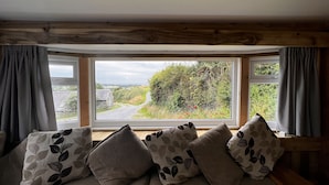 A room with a large window, a wooden ceiling, and a sofa with patterned cushions.