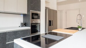 A modern kitchen with a black countertop, stainless steel appliances, and a wooden cutting board. - The Best Rent - Gorgeous two-bedroom apartment close to Cinque Giornate square (Milano)