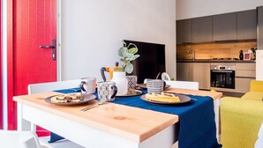 A dining table with a blue tablecloth, a red door, and a kitchen in the background. - The Best Rent - Apartment close to Porta Romana (Milano)