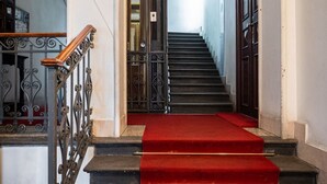 A staircase with a red carpet leading to a door with a metal gate. - The Best Rent - Two bedroom apartment close to Sondrio metro station (Milano)