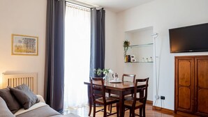 A modern living room with a sofa, a dining table with chairs, a TV mounted on the wall, and a cabinet. - The Best Rent - Two bedroom apartment close to Sondrio metro station (Milano)