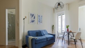 A modern living room with a blue sofa, a dining table with chairs, and artwork on the wall. - The Best Rent - Apartment in Piazza Cinque Giornate (Milano)
