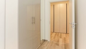 Un intérieur moderne avec une cloison en verre, un plancher en bois et une porte coulissante dotée d’une poignée verticale.