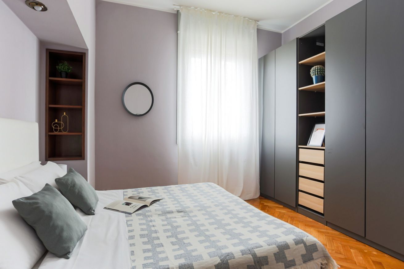 Une chambre à coucher comprenant un lit, une table de chevet, une armoire et une fenêtre avec des rideaux.