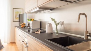 Een moderne keuken met houten kastjes, een zwart aanrecht, een roestvrijstalen spoelbak en een magnetron.