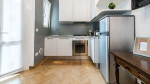 A modern kitchen with white cabinets, a stainless steel refrigerator, and a built-in oven. - The Best Rent - Two-bedroom apatment in Milan (Milano)