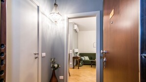 A hallway with a wooden floor, a vase with flowers, and a chandelier. - The Best Rent - Two-bedroom apatment in Milan (Milano)
