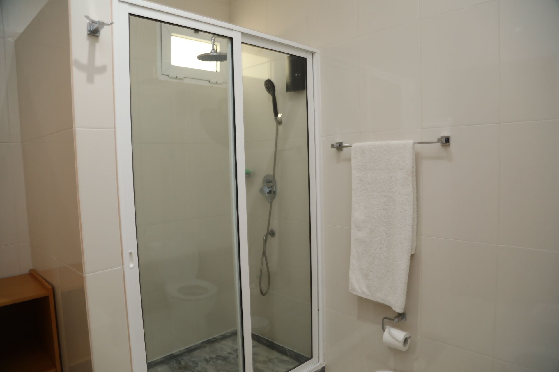 A glass-enclosed shower with a handheld showerhead and a wall-mounted faucet.