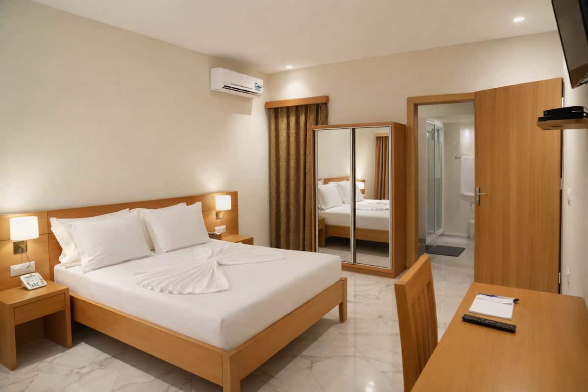 Une chambre d’hôtel équipée d’un lit, de tables de chevet, d’un bureau, d’un miroir et d’un appareil de climatisation.