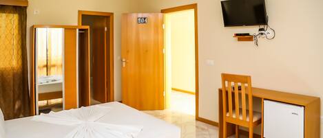 Ein Hotelzimmer mit Bett, Schreibtisch, Stuhl, Fernseher und Kleiderschrank.