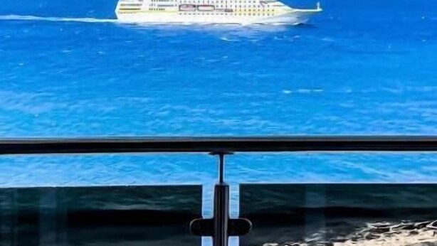 A cruise ship in the distance with a clear view of the ocean and a mountainous island in the background. - Cruzeiro Guest House (São Filipe)