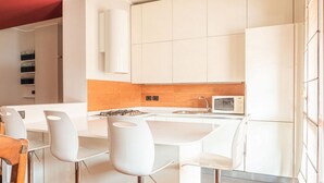 Una cocina moderna con armarios blancos, una isla central y taburetes de bar.