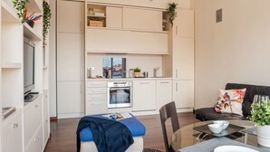 Ein kompakter Wohnraum mit Küchenzeile, Essbereich und einer Sitzecke mit Sofa und Sesseln.