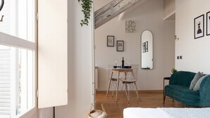 A bedroom with a bed, a window, a dining table with chairs, a mirror, and a green sofa. - The Best Rent - Nice apartment in Milan (Milano)