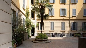 A courtyard with a palm tree, potted plants, and bicycles. - The Best Rent - Nice apartment in Milan (Milano)