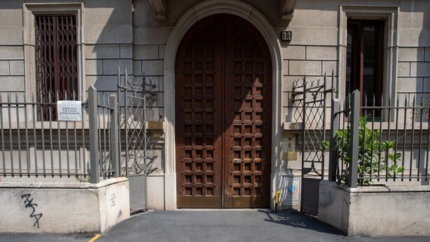 A building entrance with a large wooden double door, metal gates, and a sign indicating a parking area. - The Best Rent - Nice apartment in Milan (Milano)