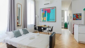 A modern hotel room with a bed, a desk, and a dining area. - The Best Rent - Rainbow apartment (Milano)