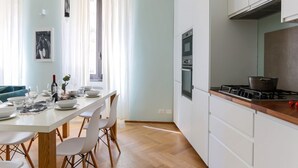 Une cuisine moderne avec des armoires blanches, un plan de travail en bois et un four encastré.